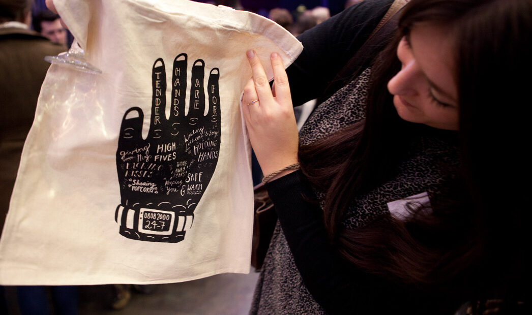 A woman holding up an illustrated tote bag
