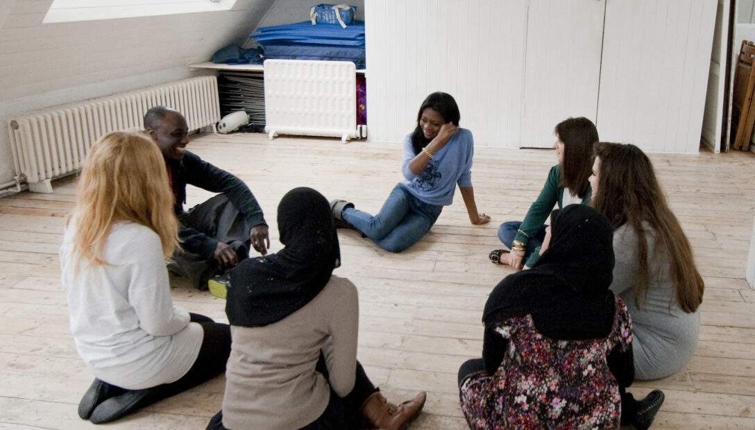 Young adults sat in a circle at a drama workshop