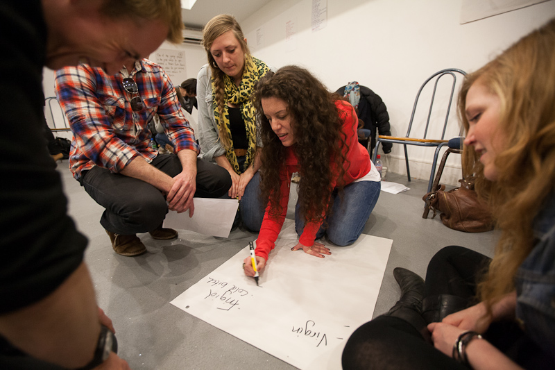 Workshop participants in a circle writing on flip-chart paper